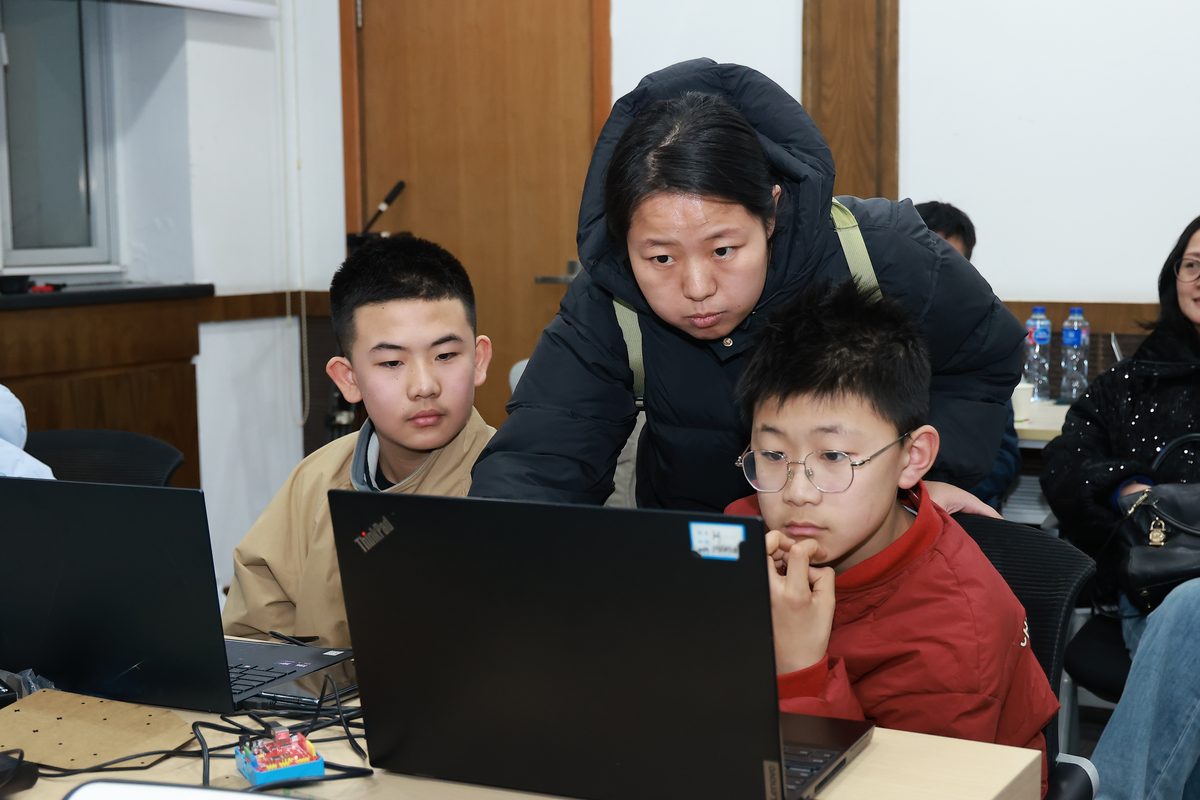 老师俯身指导学生调试程序
